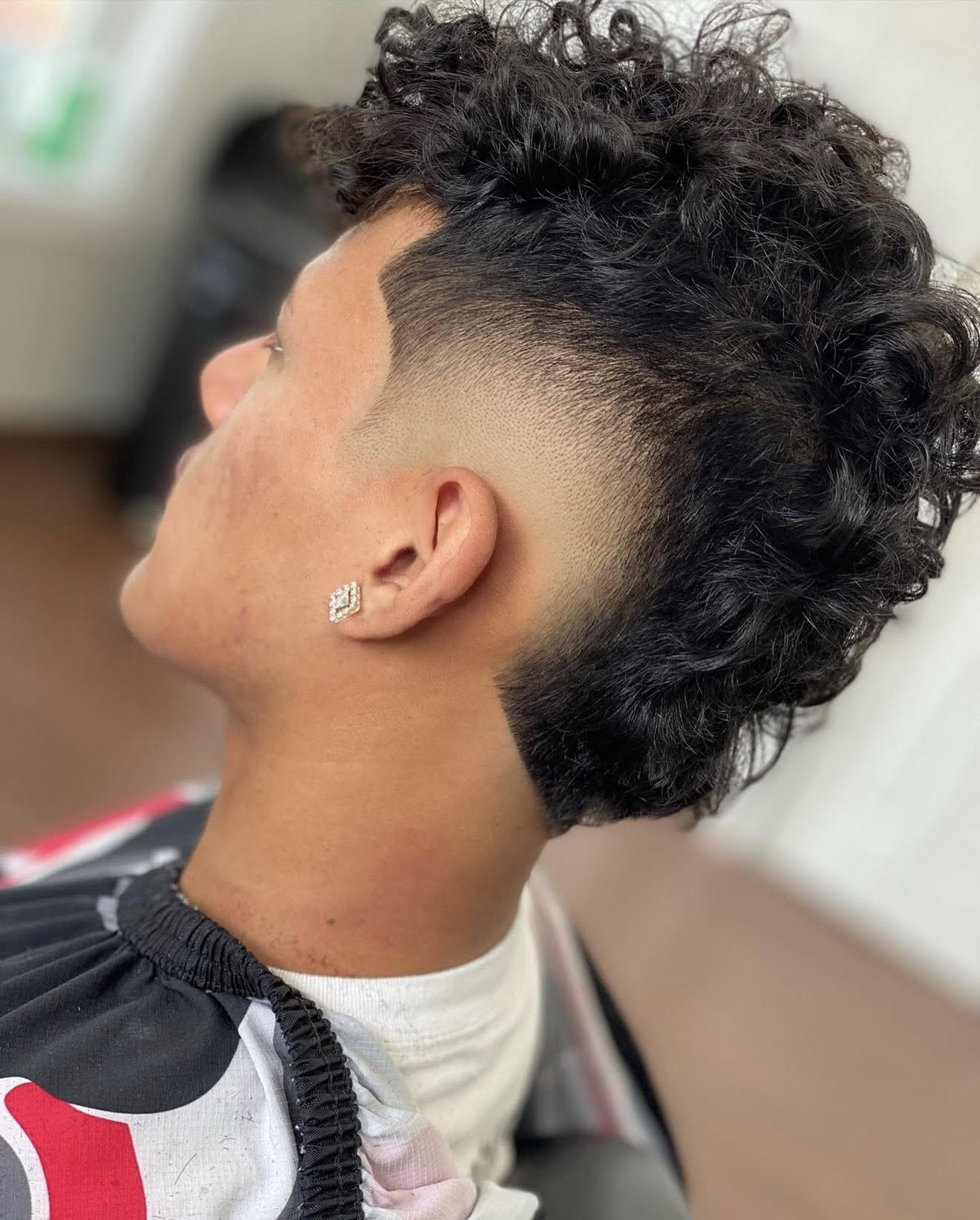 Side profile of a curly hair mid fade with a sharp temple lineup and natural curls left on top, cut at Clean Cut Studio barbershop in Brockport NY