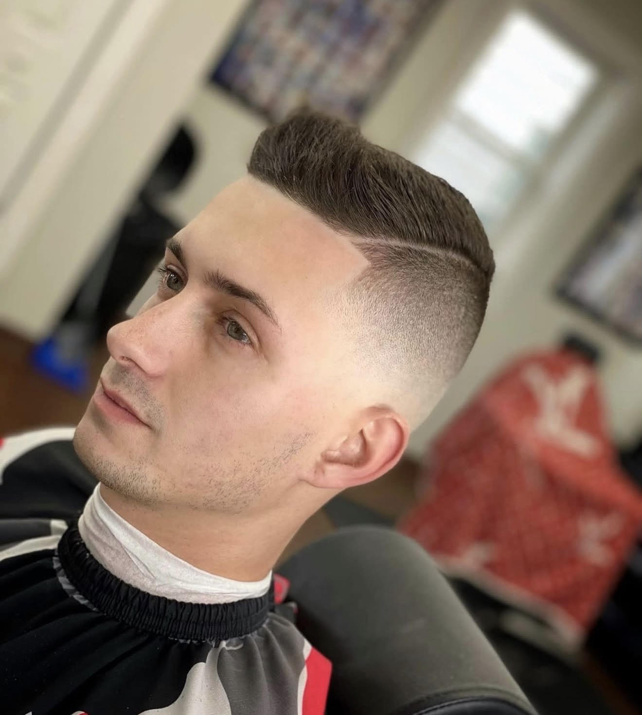 Front-side view of a high skin fade with a hard part and styled combover on top, showing clean razor lines cut at Clean Cut Studio barbershop in Brockport NY